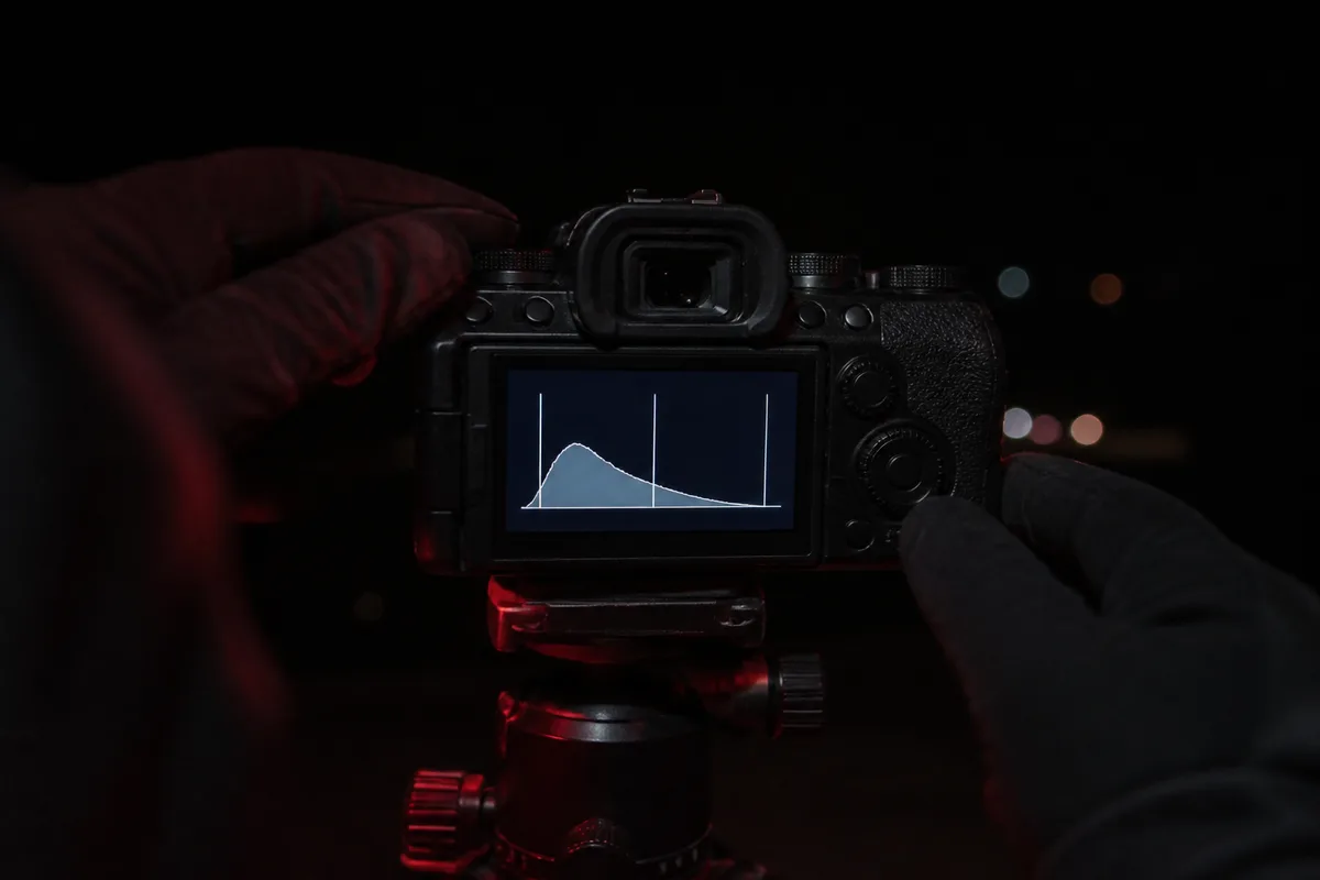 Écran arrière d&rsquo;un appareil photo posé sur trépied affichant un histogramme, dans l&rsquo;obscurité